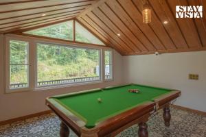 a room with a pool table in front of a window at StayVista at Ved Vilas in Kīar