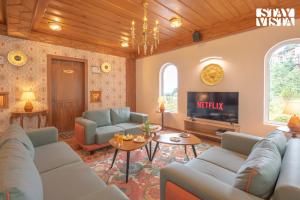 a living room with couches and a tv at StayVista at Ved Vilas in Kīar