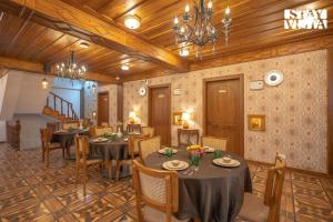 a dining room with tables and chairs and a chandelier at StayVista at Ved Vilas in Kīar