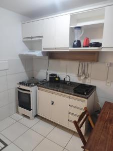 a kitchen with white cabinets and a sink and a stove at Cantinho da harmonia-Morada Nova in Petrolina