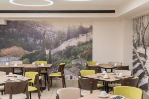 a restaurant with tables and chairs and a large painting at Trofonios Boutique Hotel in Livadeia