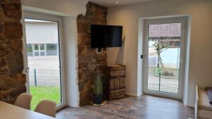 a living room with a tv on a stone wall at Modernes Apartment im grünen in Kleines Wiesental +4 photos