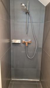 a shower with a hose attached to a tiled wall at Modernes Apartment im grünen in Kleines Wiesental