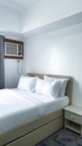 a bed with white pillows and a air conditioner at Modern Comfort Studio with City Views in Molo