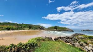 a beach with people on the sand and the ocean at Apartamento Mirador Playa de Barro in Barro de Llanes