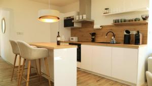 a kitchen with white cabinets and a table with a bottle of wine at Petříkovy Apartmány in Bulhary