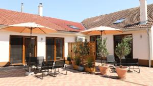 a patio with chairs and umbrellas in front of a house at Petříkovy Apartmány in Bulhary