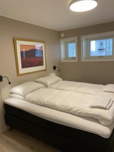 Un dormitorio con una cama grande con sábanas blancas. en Modern apartment with mountain and sea view, en Svolvær 27 fotos más