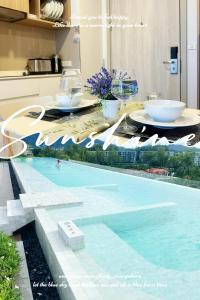 a table with bowls and wine glasses next to a swimming pool at BangTao Rooftop Seaview Laguna Skypark Condominium in Laguna Phuket
