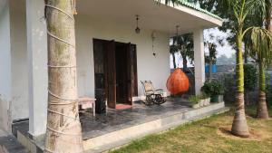 a house with a porch with a bench and a tree at Saanjh Farm in Gurgaon