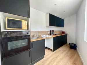 a small kitchen with a sink and a microwave at Le Cosy Tranchais - city center - 300 m beach in La Tranche-sur-Mer