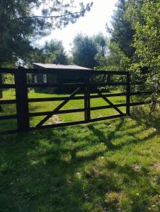 a wooden fence in a field with a house in the background at Zacisze the Skuzos in Zdbice