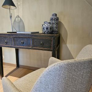 a dresser with vases and a lamp and a chair at LA BELLE IDEE in Nokere