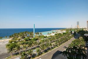 une rue avec des palmiers et une plage avec l'océan dans l'établissement The Venue Jeddah Corniche, à Djeddah