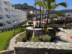 a garden with palm trees and a building at Apartamento Victoria in Mogán