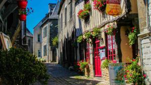 an alley in an old town with red doors and flowers at Ty Breizh - Studio cosy au cœur de Dol-de-Bretagne in Dol-de-Bretagne