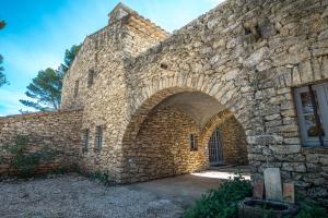 a large stone building with an archway in it at Stunning panoramic views and heated pool in Roussillon in Roussillon