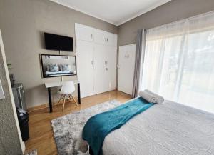 a bedroom with a bed and a desk and a television at Zhantique Guest House 2- Unit 5 in Boksburg