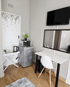 a living room with a white table and a tv at Zhantique Guest House 2- Unit 5 in Boksburg