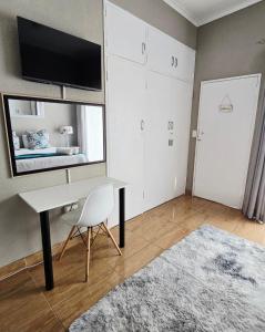 a room with a desk and a tv on a wall at Zhantique Guest House 2- Unit 5 in Boksburg +23 photos