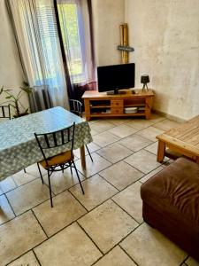 a living room with a table and a television at Charming Village House in the Heart of Isle-sur-la-Sorgue in LʼIsle-sur-la-Sorgue