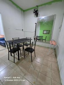 a table and chairs in a room with a green screen at Rumah Kak Ana in Pasir Puteh