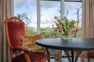 a table and chairs with a vase of flowers and a window at Logement de Appelgaard in Culemborg