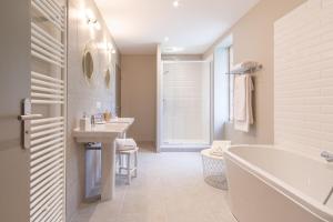 a bathroom with two sinks and a tub and a bath tub at Chambres d'hôtes du Château de Seguin in Lignan-de-Bordeaux +5 photos