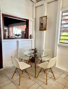 a dining room with a glass table and chairs at Villa Surf Kreol moderne à 3 min du Souffleur in Port-Louis
