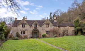 an old stone house with a grass yard at Preedy's Cottage in Castle Combe