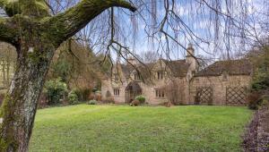 a large stone house with a grass yard at Preedy's Cottage in Castle Combe