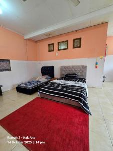 two beds in a room with a red carpet at Rumah Kak Ana in Pasir Puteh