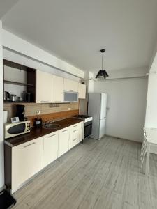 eine Küche mit weißen Schränken und einem Kühlschrank in der Unterkunft Militari Confort Suites in Roşu