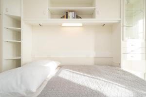 a white bedroom with a bed and shelves at Happy Place in Bojendorf