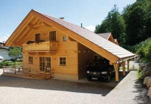 a large wooden house with a car parked outside at Achenseer Hüttendörfl in Häusern