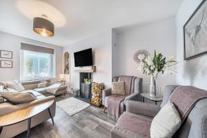 a living room with a couch and chairs and a tv at Ty Mawr, Great Orme in Llandudno