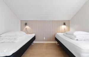 Dos camas en una habitación con dos lámparas en la pared. en Cozy Home In Løgstør With Sauna, en Trend