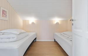 Dos camas en una habitación pequeña con paredes blancas. en Cozy Home In Løgstør With Sauna, en Trend