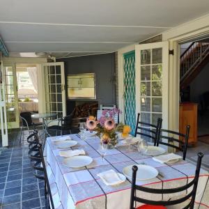 une grande table avec des assiettes et des fleurs dans l'établissement Jaco and Liz's sea get away, à Hermanus