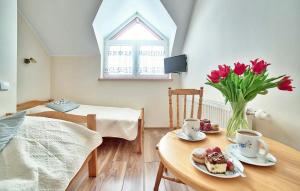 Zimmer mit einem Tisch mit einer Vase roter Blumen in der Unterkunft 1 Bedroom Lovely Apartment In Golubie in Pierszczewo