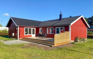 a red house with a deck in a yard at 5 Bedroom Awesome Home In Löttorp in Böda