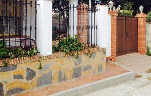 a wrought iron fence with a stone wall and a wooden gate at 2 Bedroom Beautiful Home In Benalmadena in Benalmadena Costa