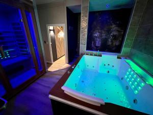 a jacuzzi tub in a room with blue lights at Suite KalypsÔ, romantisme, balnéo et sauna privé in Quimperlé +66 photos