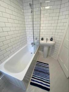 a white bathroom with a tub and a sink at Oyster Catchers in Ryde