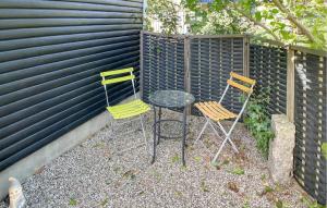 FaldsledにあるBeautiful Home In Millinge With Wifiのフェンスの横に3脚の椅子とテーブル