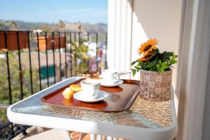 ein Tablett mit Tassen und Untertassen auf einem Tisch auf einem Balkon in der Unterkunft Encanto en Iznájar con terraza y vistas a la montaña in Iznájar