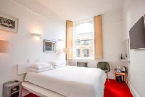 a white bedroom with a white bed and a window at Kellys Hotel in Dublin