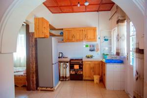 een keuken met een witte koelkast en houten kasten bij Cozy 3 bedroom house in Huye