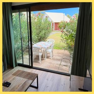 Ti Caz Lagon I T2 I piscine Front de mer Hermitage في Saint-Paul: فناء مع طاولة وكراسي خارج باب زجاجي منزلق