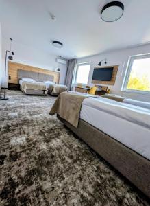 une grande chambre avec deux lits et une télévision à écran plat dans l'établissement Hotel Eden, à Rzgów